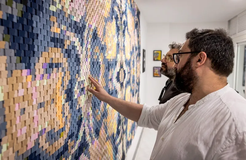 Visitors looking closely at the assembled surface of ReTapestry No. 3 by Matthew Joseph Casha.