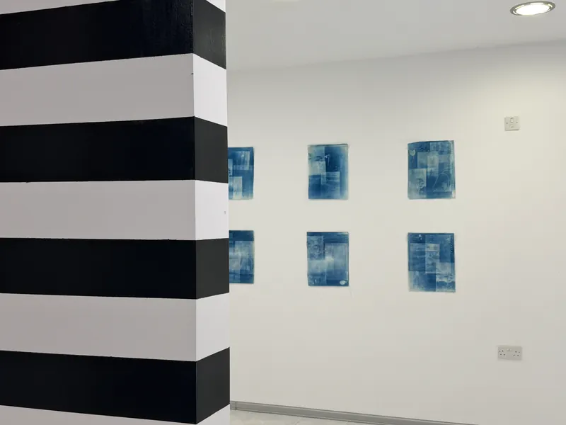 Blue works on paper displayed beside a striped column in the New Renaissance Malta showroom.